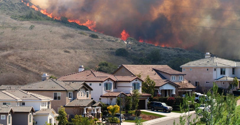 Fire burning on hillside with houses in the forefront