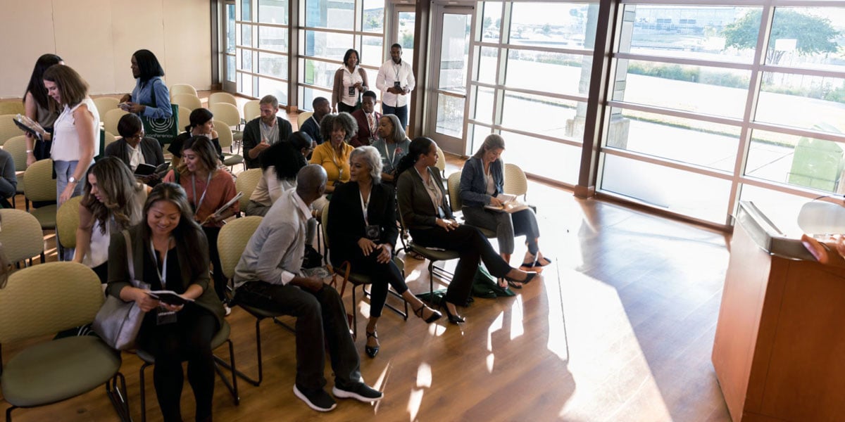 Community members sit in chairs at local town hall meeting