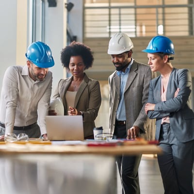 group reviewing laptop in hard hats