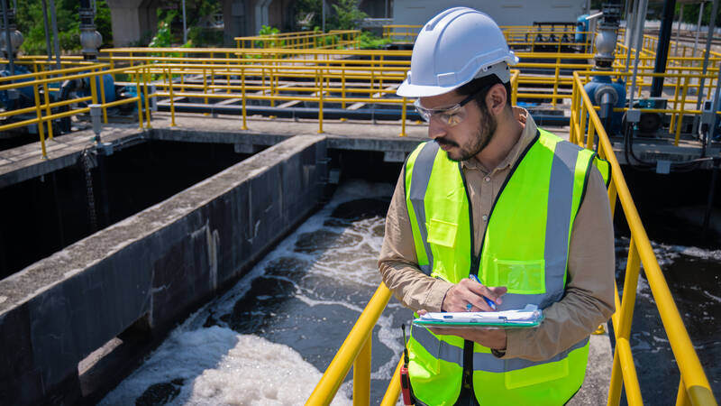 Inspector in white hat examines stormwater treatment