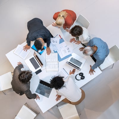 team-standing-around-table-looking-at-plans