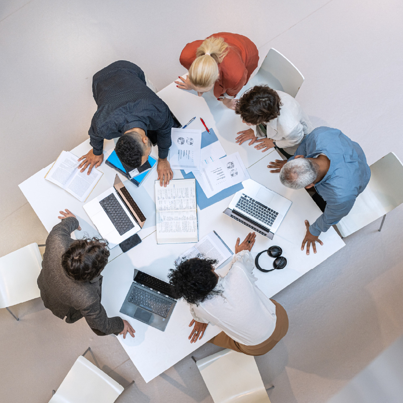 team-standing-around-table-looking-at-plans